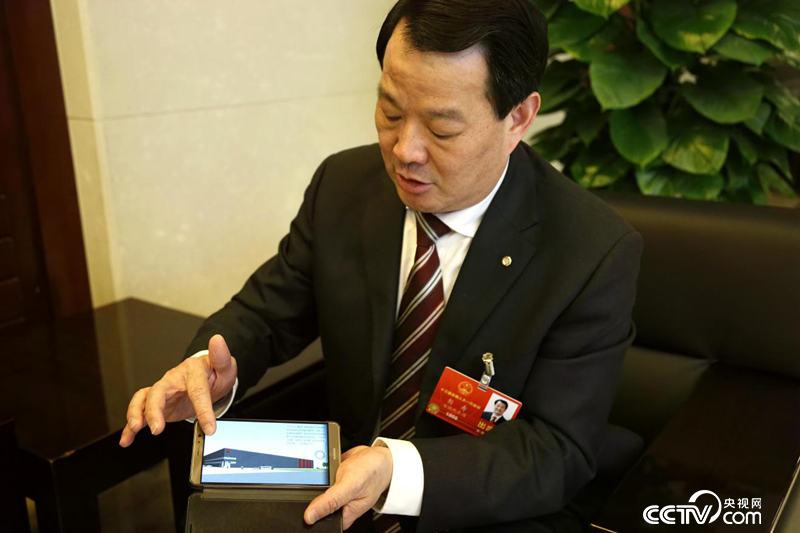 Peng Shou, a deputy to the National People's Congress, showed reporters a factory with power generation glass as its external wall. (Li Wenliang/photo)